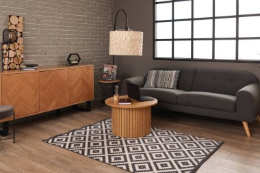 Kahve masasında siyah kanepe ve modern dizüstü bilgisayarı olan şık bir oturma odası.