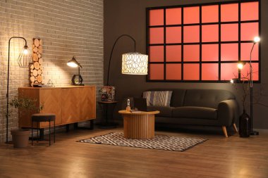 Kahve masasında siyah kanepe ve modern dizüstü bilgisayarı olan şık bir oturma odası.