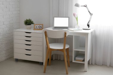 Modern dizüstü bilgisayarı ve pencerenin yanında güzel sümbül çiçekleri olan rahat bir iş yeri.