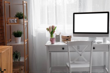 Modern bilgisayar ve pencerenin yanındaki güzel sümbül çiçekleriyle rahat bir iş yeri.