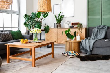 Büyük pencerenin yanında rahat koltukları ve masası olan şık bir oturma odası.