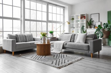 Büyük pencerenin yanında rahat kanepeleri ve kahve masası olan parlak bir oturma odası.