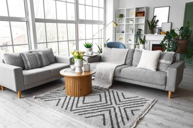 Büyük pencerenin yanında rahat kanepeleri ve kahve masası olan parlak bir oturma odası.