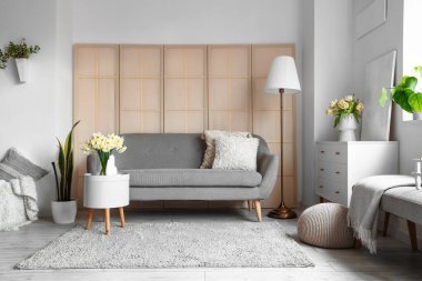 Gri kanepesi, çekmecesi ve lambası olan oturma odasının içinde.