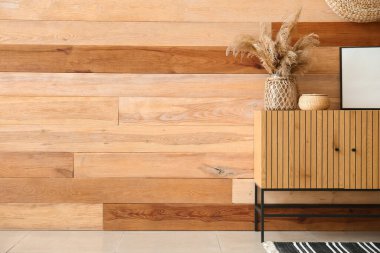 Boş çerçeveli çekmeceler, sepet ve pampa otları odasındaki ahşap duvarın yanında.