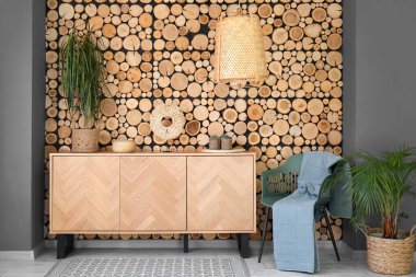 Odanın içinde ahşap klozet, ev bitkileri ve koltuk var.