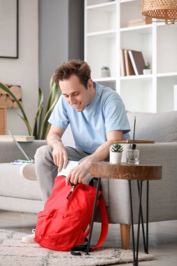 Evde sırt çantalı bir erkek öğrenci.