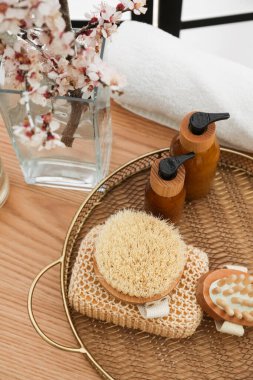 Çiçek açan dalları ve banyo aksesuarları olan bir vazo.