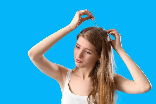 青い背景で髪の成長のための血清を使用して若い女性 — ストック写真