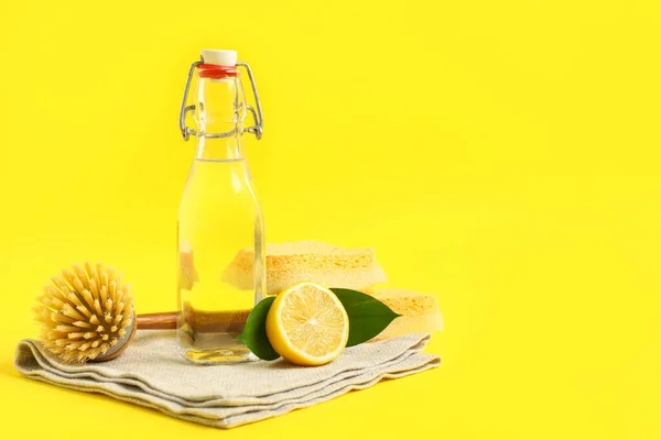 stock image Bottle of vinegar, sponges, brush, napkin and lemon on yellow background