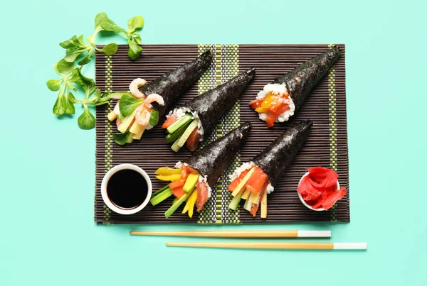Bambusmatte Mit Leckeren Sushi Zapfen Sojasauce Und Feldsalat Auf Farbigem — Stockfoto