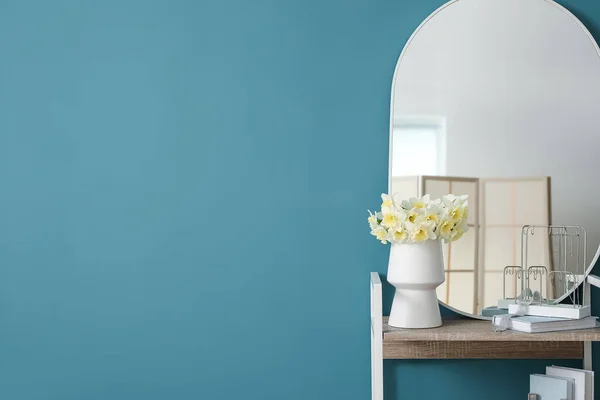 青い壁の近くの花瓶や鏡にナルシシズムの花と棚ユニット — ストック写真