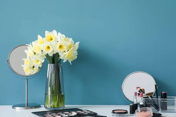 青い壁の近くに異なる化粧品やナルシシズムの花を持つテーブル — ストック写真