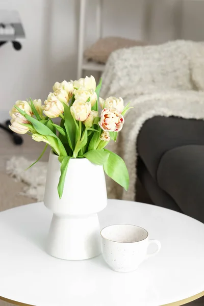 リビングルーム内のコーヒーテーブルの上のチューリップの花とカップの花瓶 — ストック写真