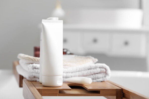 Tray with towels and cosmetic products in bathroom