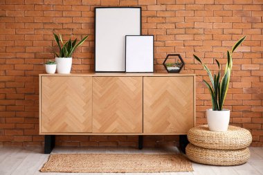 Boş çerçeveli ahşap dolap ve kahverengi tuğla duvarın yanında bitkiler.