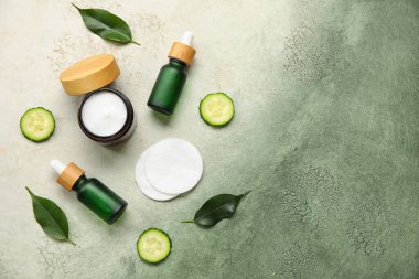 Doğal kozmetik ürünleri, pamuk pedleri ve grunge arkaplanda salatalık bileşimi