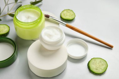 Doğal krema kavanozları ve ışık arkaplanındaki malzemelerle kompozisyon