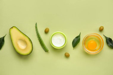 Yeşil zemin üzerinde doğal krema ve malzemeler bulunan kompozisyon