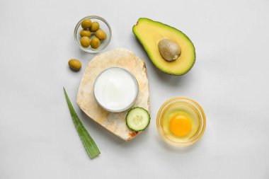 Açık arkaplanda doğal krema kavanozu ve malzemelerle kompozisyon