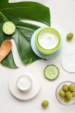 Kavanozlar dolusu doğal krema, malzemeler ve arka planda palmiye yaprağı.