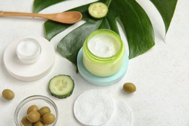 Doğal krema kavanozları, malzemeler, pamuk bloknotlar ve arka planda palmiye yaprağı kompozisyonu