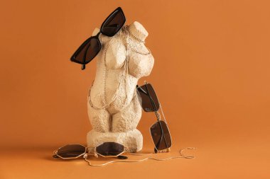 Şık güneş gözlüklü heykel ve kahverengi arka planda mücevherler