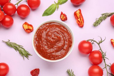 Bir kase leziz domates sosu ve leylak arkaplanda bulunan malzemeler.