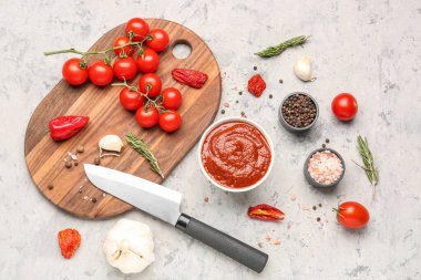 Gri masadaki domates sosu ve malzemelerle kompozisyon.