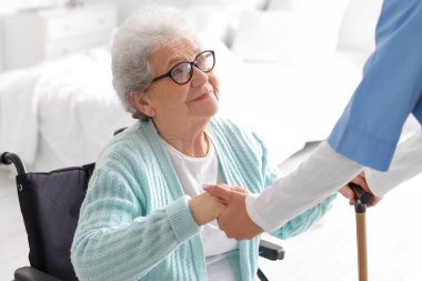 Tekerlekli sandalyedeki yaşlı kadın evde bakıcısıyla.