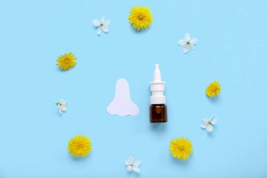 Kağıt burunlu bir şişe damla ve mavi arka planda çiçekler. Mevsimsel alerji kavramı