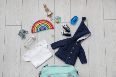 Hafif ahşap arka planda bebek için şık kıyafetler ve oyuncaklar