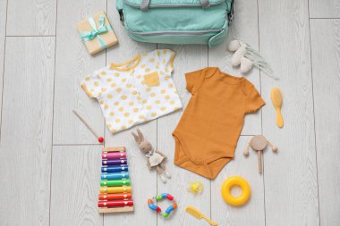 Hafif ahşap arka planda bebek için şık kıyafetler ve oyuncaklar