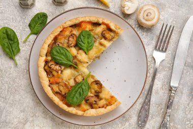 Beyaz grunge masasında ıspanak yapraklı mantar turtası ve çatal bıçak takımı.