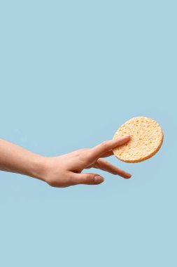 Açık mavi arkaplanda makyaj temizliği için süngerli el