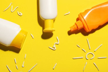 Sarı arka planda güneş kremiyle çizilmiş güneş kremi çizimleri