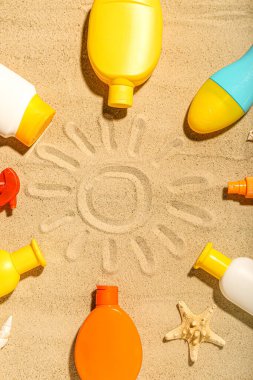 Kum üzerindeki farklı güneş kremlerinden yapılmış çerçeveli yaratıcı bileşim