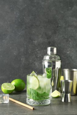 Bir bardak taze mojito, çalkalayıcı ve arka planda jigger.