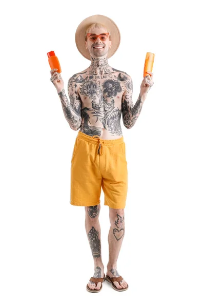 Tattooed man with different sunscreen creams on white background