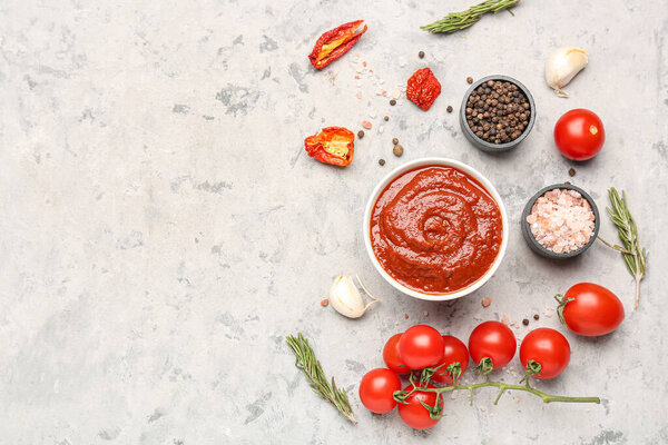 Composition with bowl of tomato sauce and ingredients on grey table