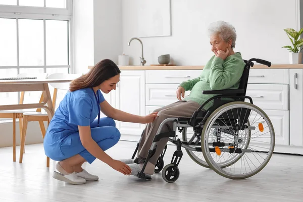 Evde Tekerlekli Sandalyede Yaşlı Bir Kadınla Genç Bir Bakıcı — Stok fotoğraf