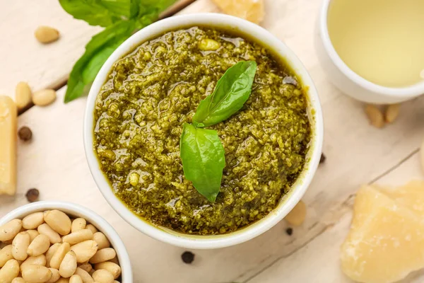 stock image Bowl of delicious pesto sauce and ingredients on white wooden table, closeup