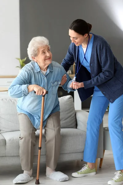 年轻的护理人员帮助老年妇女坚持在家里站立起来 — 图库照片