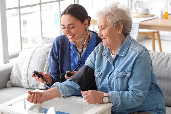 Young Caregiver Measuring Blood Pressure Senior Woman Home — Stock Photo, Image