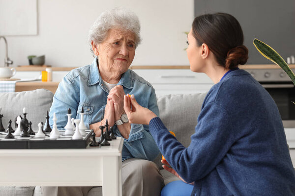 Старшая женщина принимает таблетки от сиделки дома