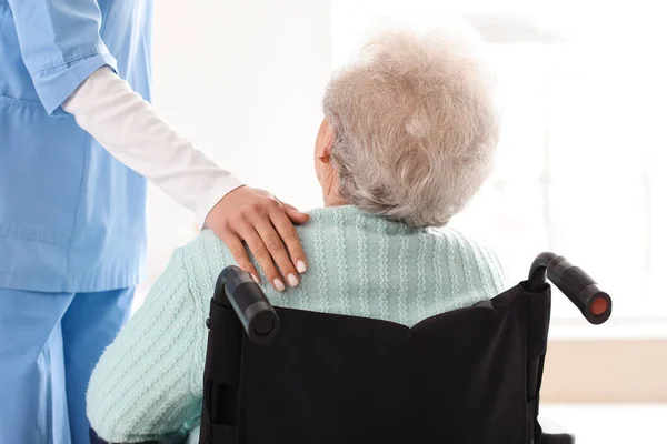 老人ホームで介護者と車椅子の女性 バックビュー — ストック写真
