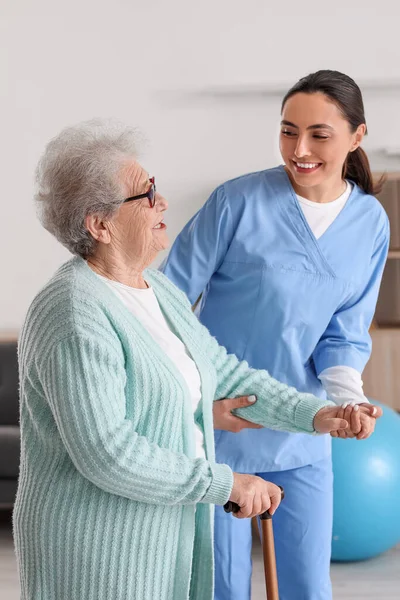 Young Caregiver Helping Senior Woman Walking Stick Home — Stock Photo, Image