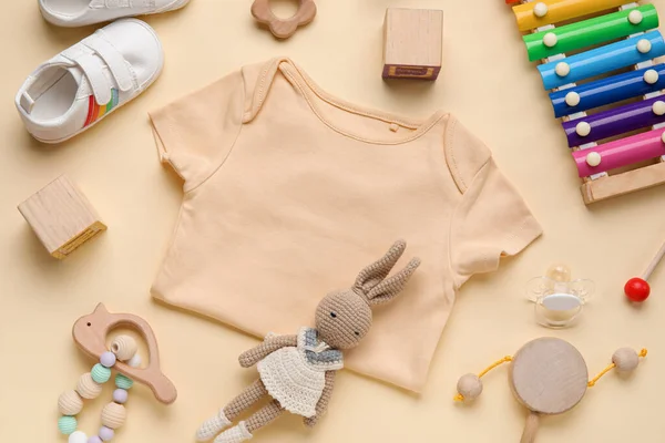 Açık Sarı Arka Planda Bebek Kıyafetleri Oyuncakları Olan Kompozisyon — Stok fotoğraf