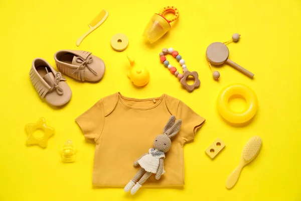 Sarı Arka Planda Bebek Kıyafetleri Oyuncaklar Aksesuarlarla Kompozisyon — Stok fotoğraf