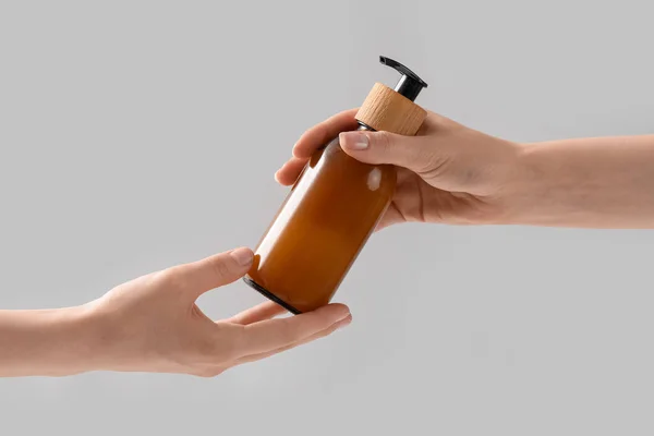 Hafif Arkaplanda Kozmetik Ürünü Şişesi Tutan Eller — Stok fotoğraf